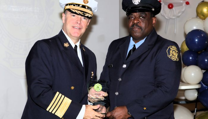 el comisario de bomberos y el bombero, ambos con uniforme de gala, reciben conjuntamente el premio al heroísmo