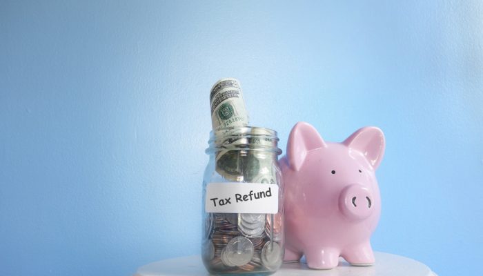 Coins and bills in a jar next to a pink piggy bank