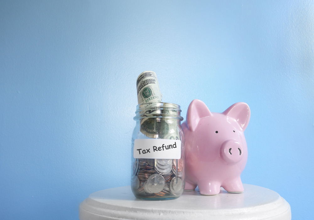 Coins and bills in a jar next to a pink piggy bank