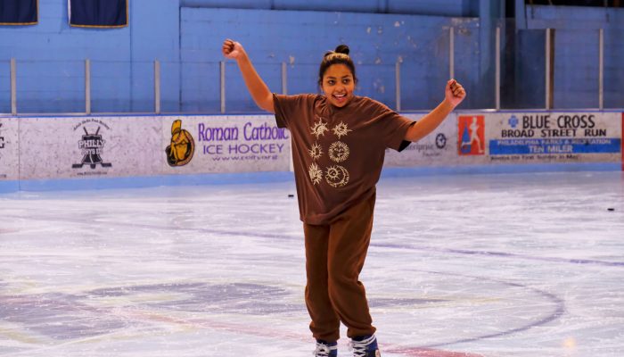 An African-American teenager smiles as she ice skates at the Rizzo Rink.