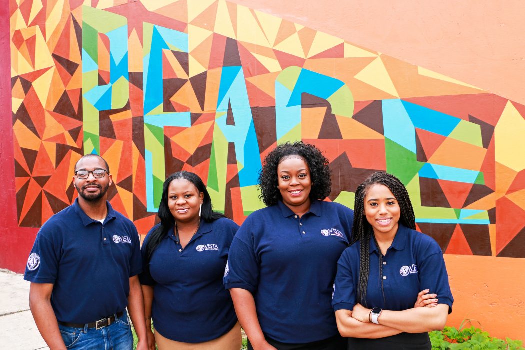 Four people stand in front of a mural