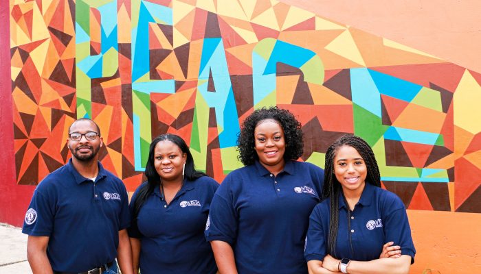 Four people stand in front of a mural