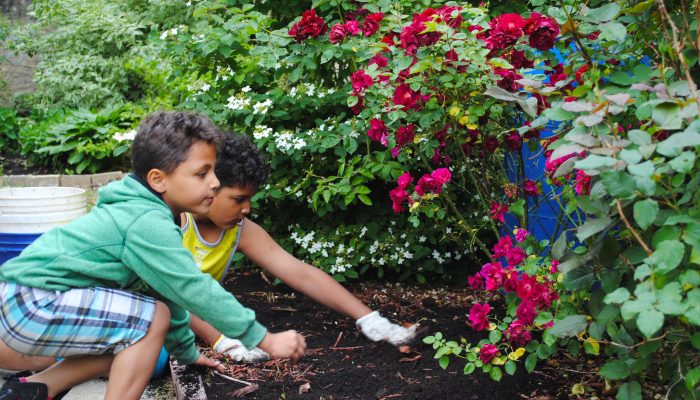 Two youth spread mulch in Benson Park during Love Your Park Week.