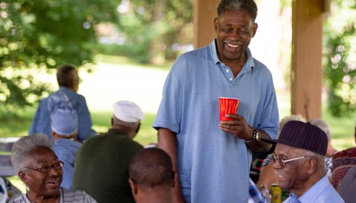 An African-American man smiles at a picnic in the park.
