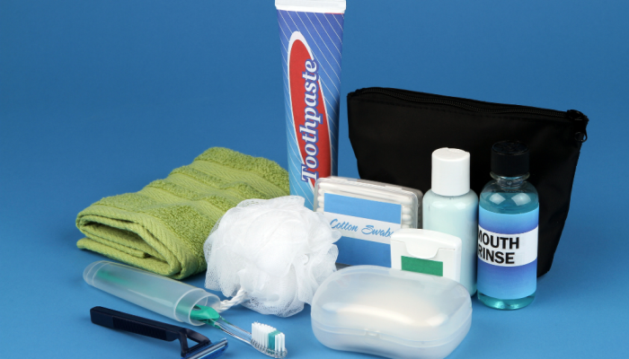 A display of toiletries. Including a towel, toothpaste, razor, soap, mouthwash, lufa, shampoo and floss.