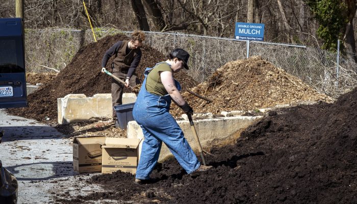 A woman and a man shovel organic materials at the Fairmount Organic Recycling Center.