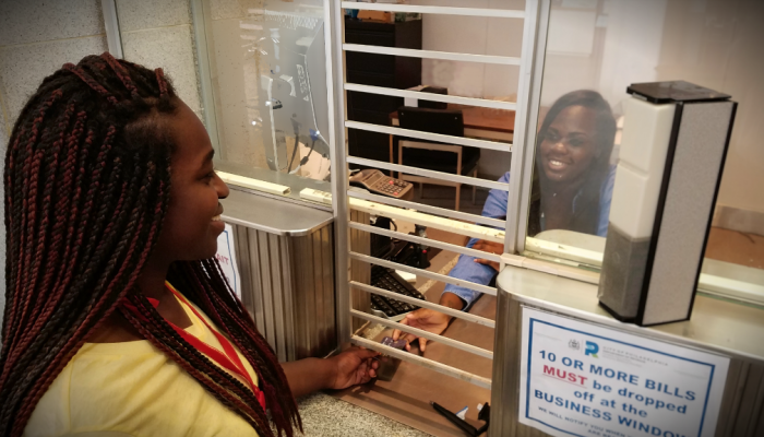A smiling woman pays a bill at a cashier's
