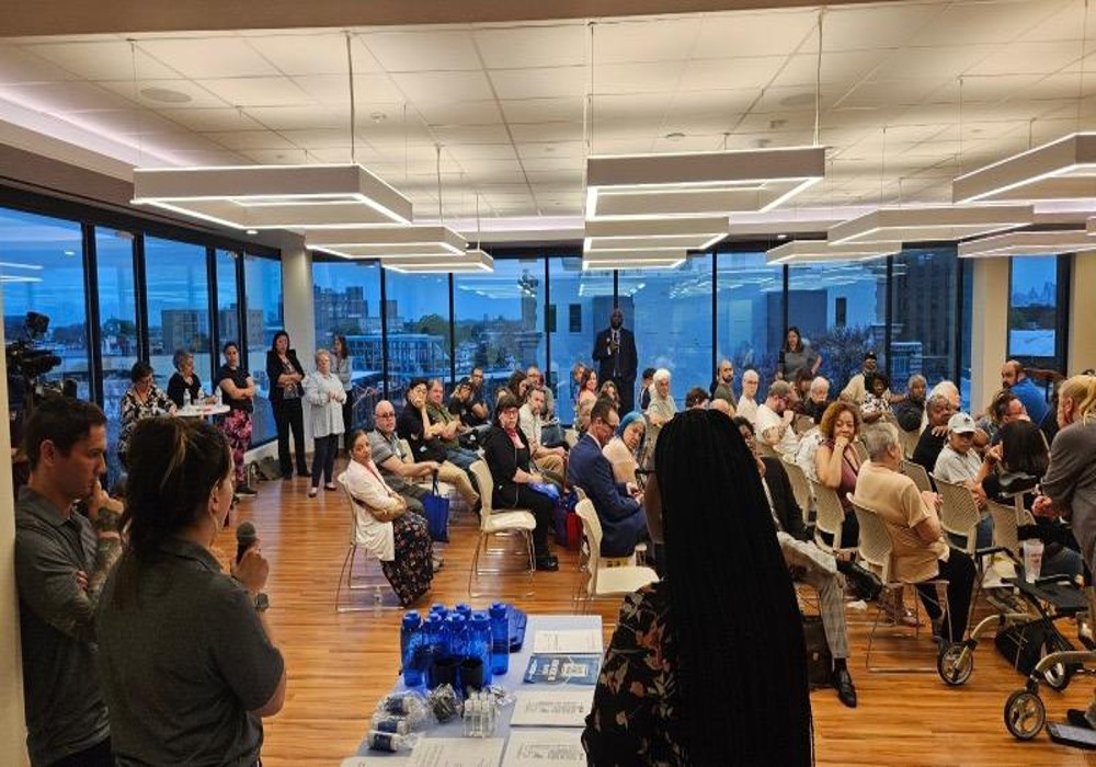 A conference room filled with people in seats listening to speakers.