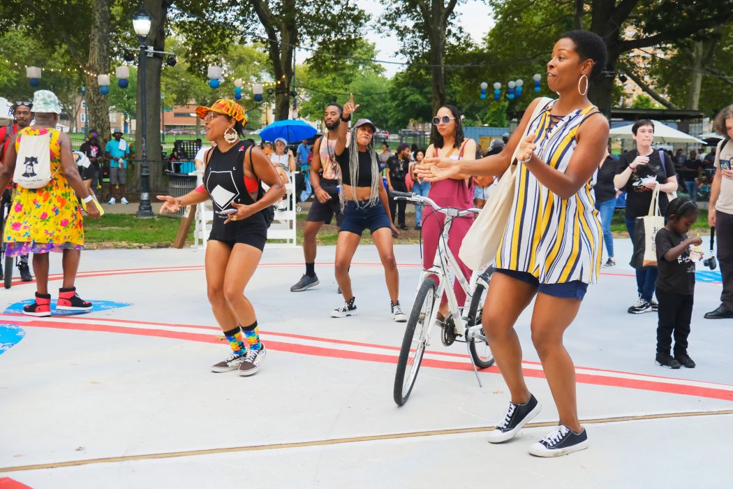 A group of adults dance on the Oval