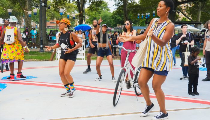 A group of adults dance on the Oval