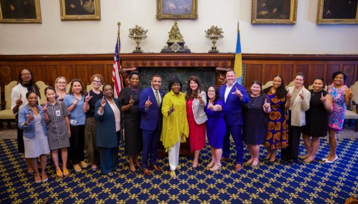 Mayor Cherelle Parker standing with members of her Administration. Everyone is holding their pointer fingers up.