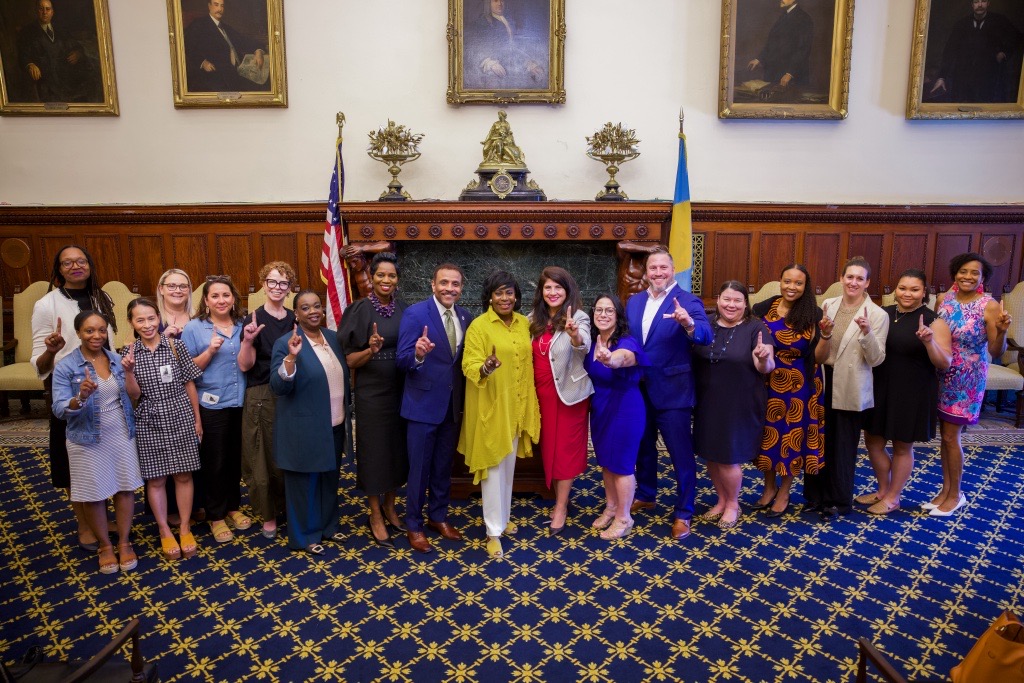 Mayor Cherelle Parker standing with members of her Administration. Everyone is holding their pointer fingers up.