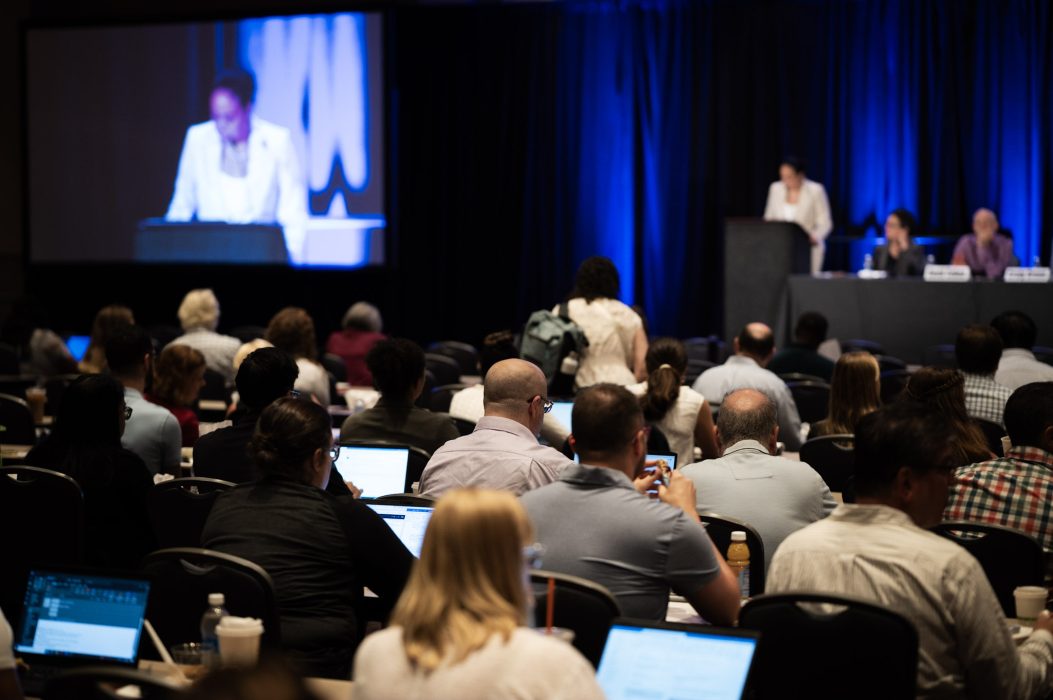 People sit in the audience of a panel discussion