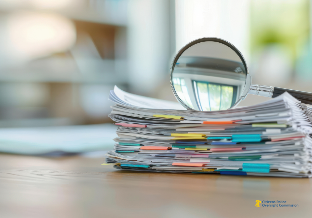 A pile of folders and notes with a large magnifying glass on top.