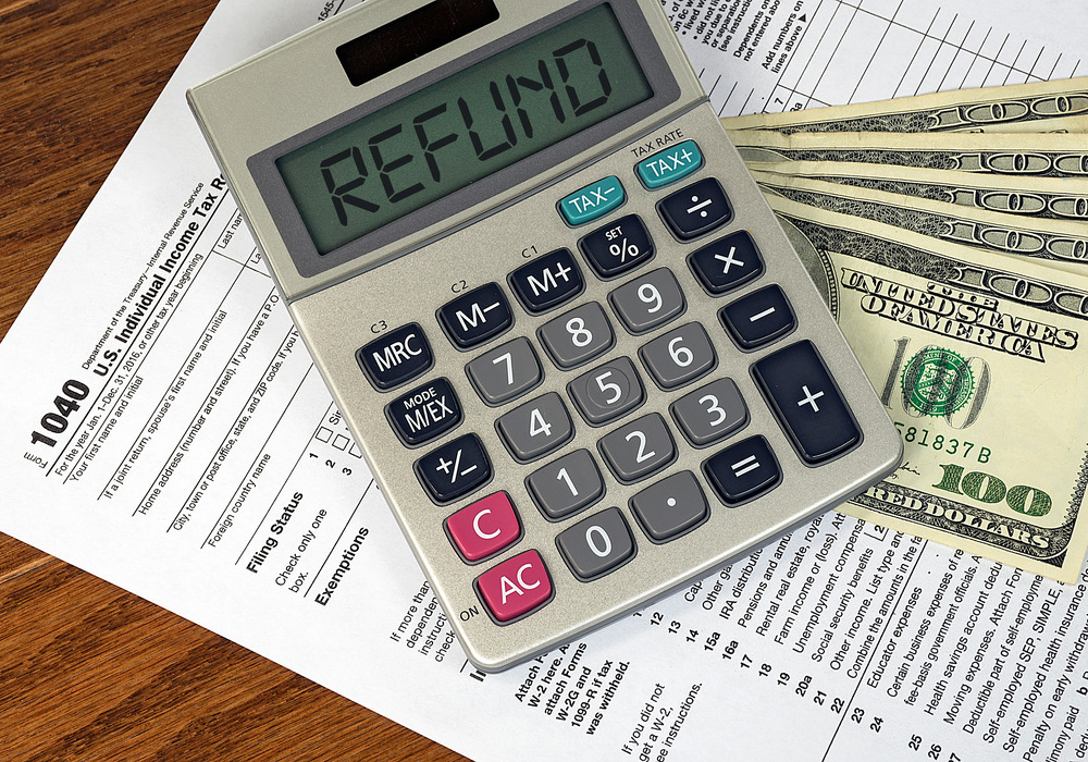 Picture of 1040 tax return, hundred-dollar bills, and a calculator with the word Refunds on it