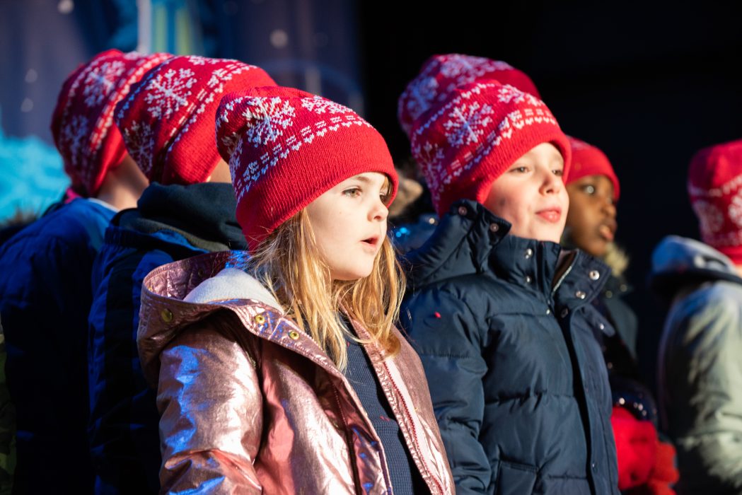 A group of young children perform on a stage.