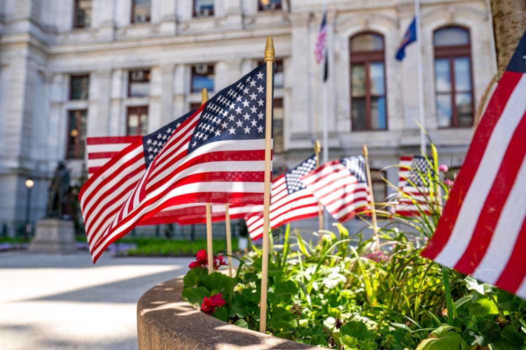 Picture of American flags in in a flowerbed at City Hall's courtyard