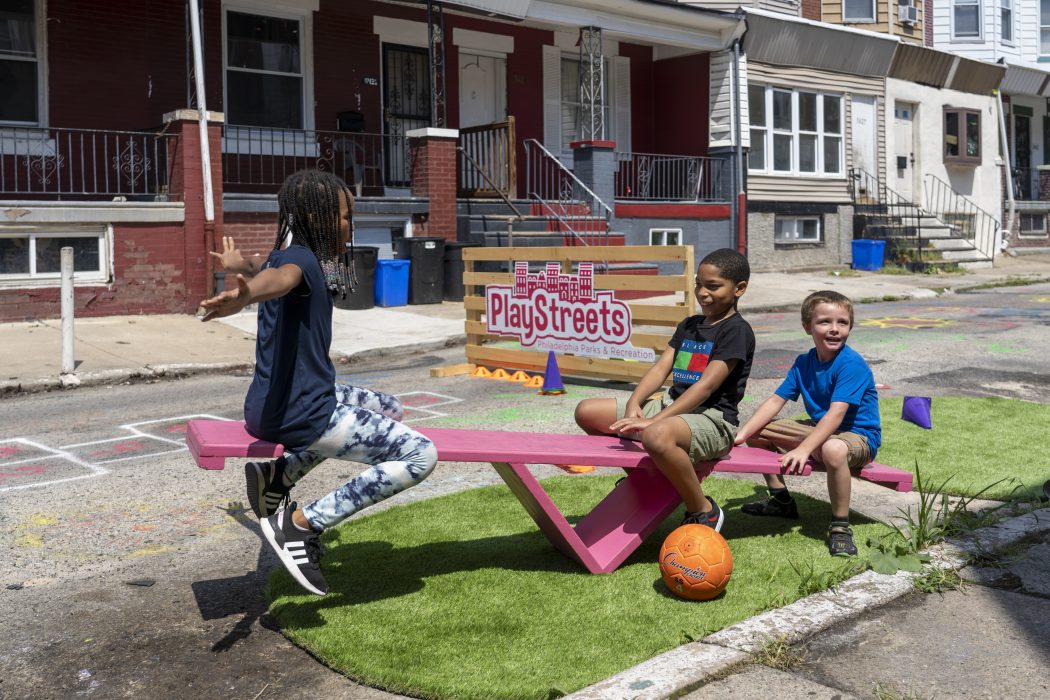 A group of young children happily playing on a seesaw.