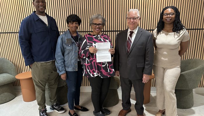 Rosie Marie Crisp holding her deed alongside Councilmember Cindy Bass staff members, Register of Wills John Sabatina, and Title Clearance Unit Myasia Williams.