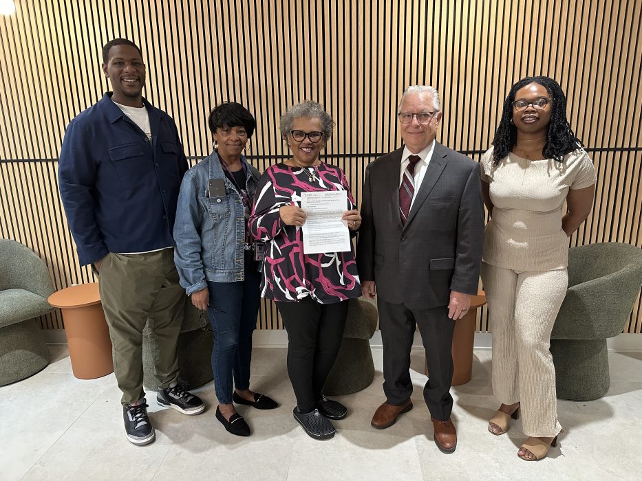 Rosie Marie Crisp holding her deed alongside Councilmember Cindy Bass staff members, Register of Wills John Sabatina, and Title Clearance Unit Myasia Williams.
