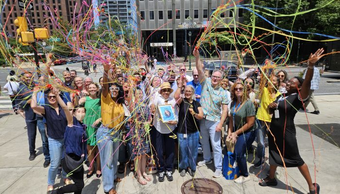 Celebratory group photo outside of One Parkway Building. The group has their hands in the air and tosses confetti