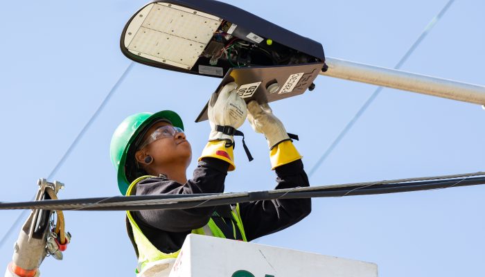 A person installing a new LED bulb into a City-owned streetlight.