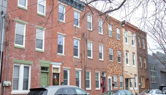 Rowhouses in a Philadelphia neighborhood with cars parked out in front.