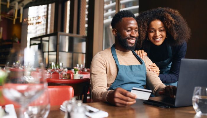 Two smiling people looking at a computer