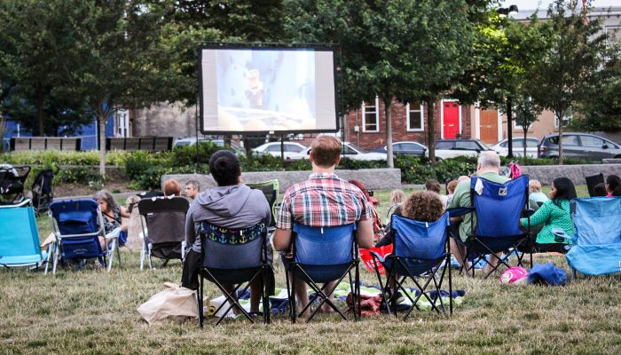A group of friends enjoy an outdoor movie screening.