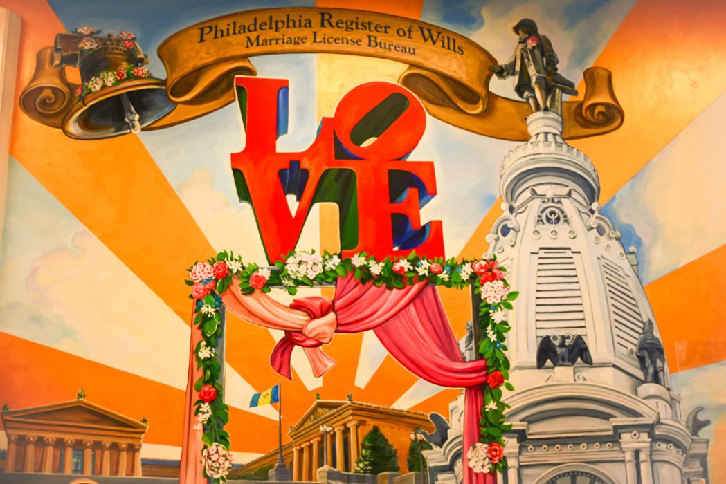 A mural of City Hall and the LOVE Sign with bells above the sign