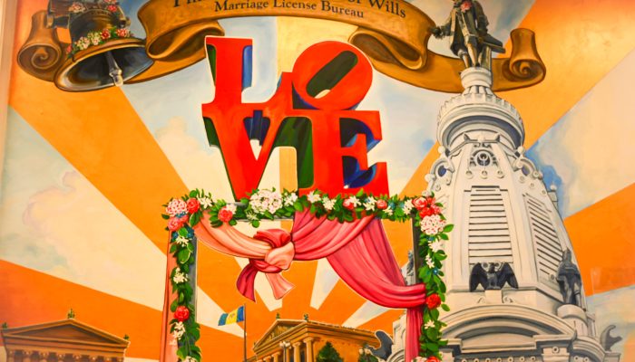 A mural of City Hall and the LOVE Sign with bells above the sign