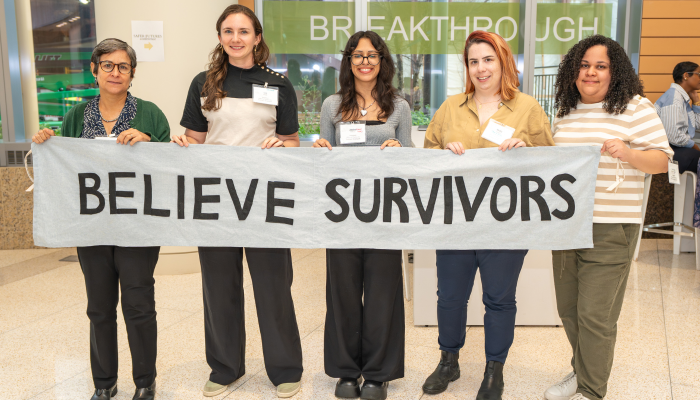 ODVS staff stand with a "Believe Survivors" banner