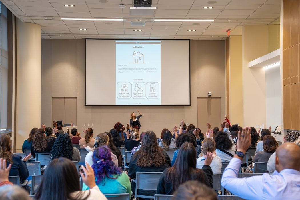 Attendees at the Safer Futures Conference participate in an interactive session, raising their hands.