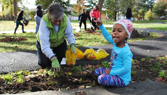 Volunteers collect leaves and clean the public park while posing for a photo.