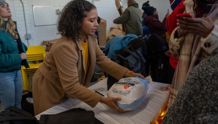 A woman places an unwrapped turkey on a table.