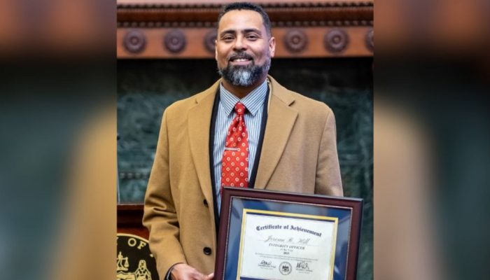 Jerome R. Hill shows his Integrity Officer of the Year Award at the Mayor's Reception Room in City Hall.