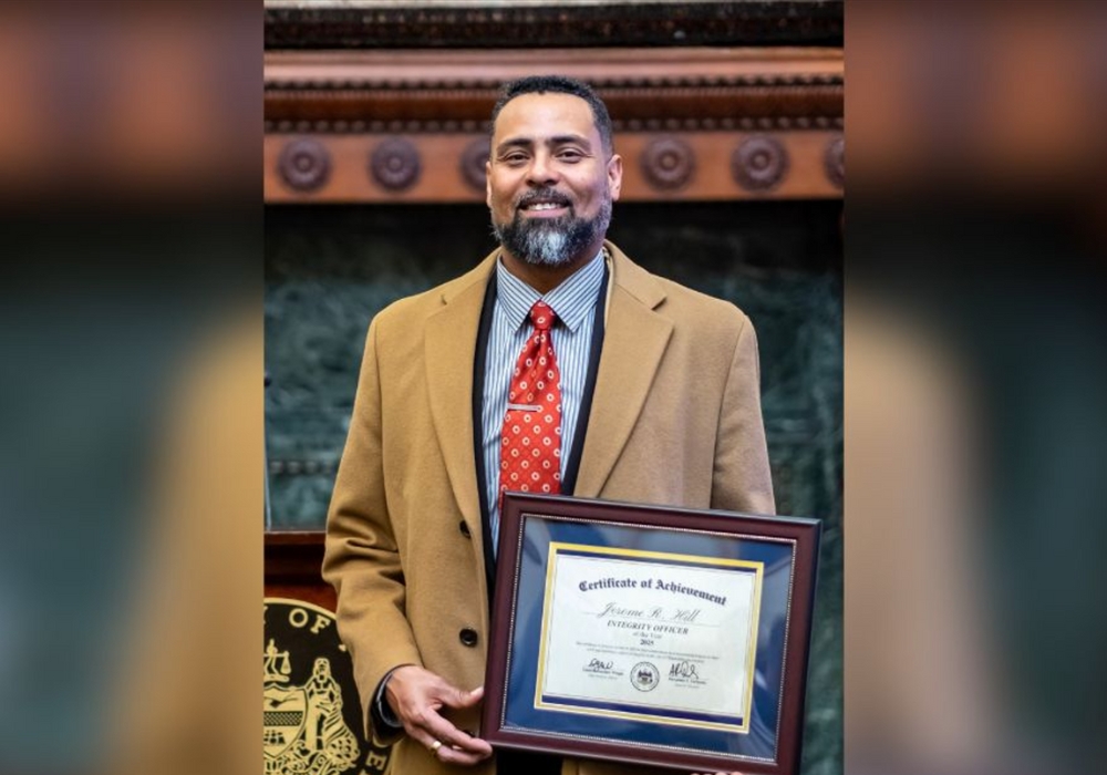 Jerome R. Hill shows his Integrity Officer of the Year Award at the Mayor's Reception Room in City Hall.