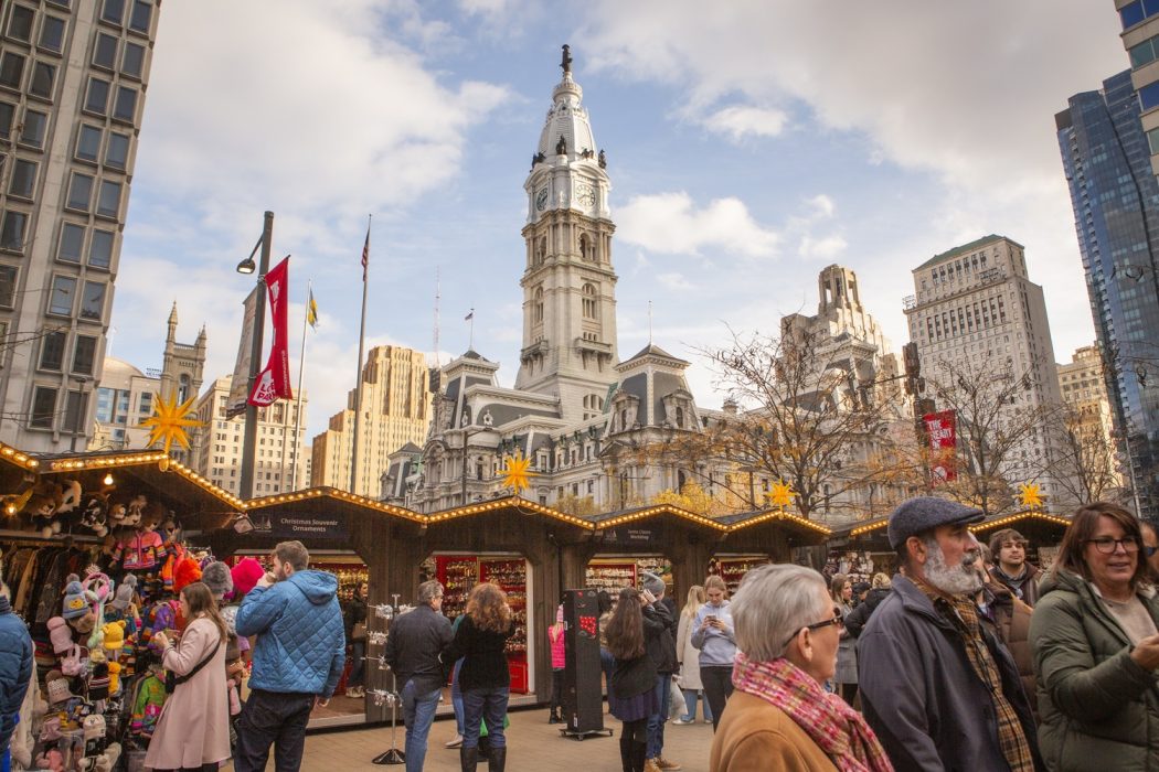 People walking around at Christmas Village with City Hall in the background