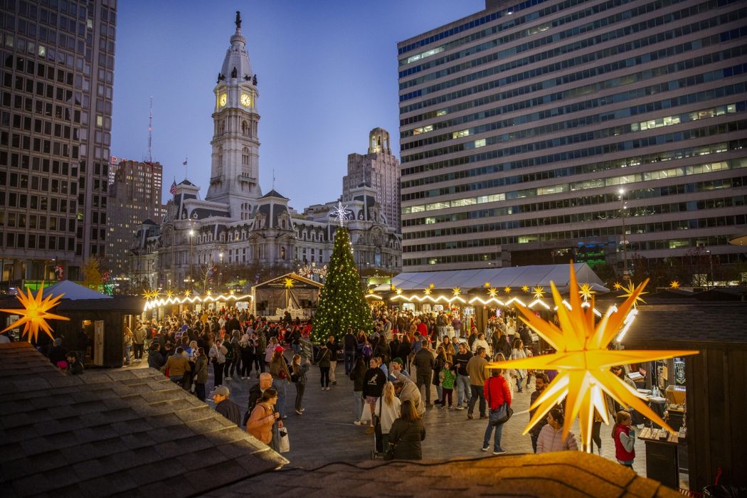 People shopping at Christmas Village in the evening with City Hall in the background