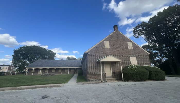 A photo of a simple brick building with a peaked roof and cream-colored trim.