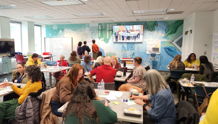 Shared Safety members gathered in a meeting. Members discuss the strategic plan in small groups at tables and use sticky notes to participate in a prioritization activity.