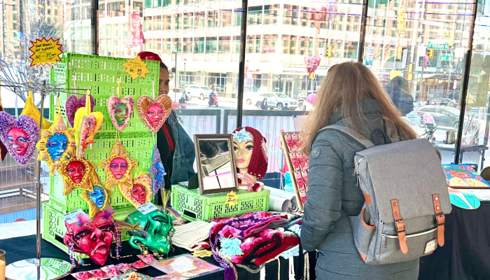 A patron visits a vendor selling heart shaped crafts.