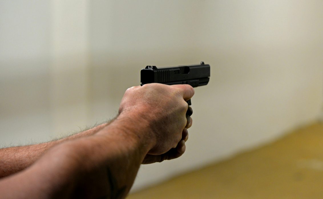 two hands extended holding a small black firearm.