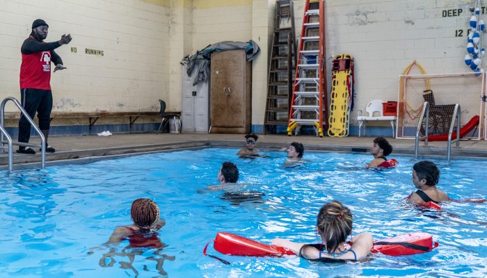 A instructor leads a group through life guard training in a pool.