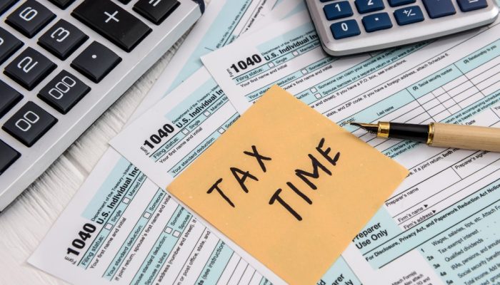 Handwritten Tax Time sticker on a 1040 form, calculators, and a pen