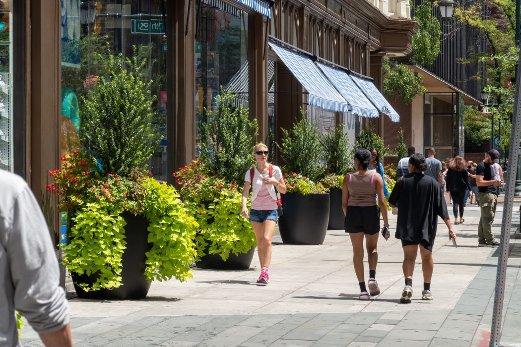 Photograph of pedestrians in front of Five Below on Market Street. It is a sunny summer's day and pedestrians wear shorts and sunglasses.