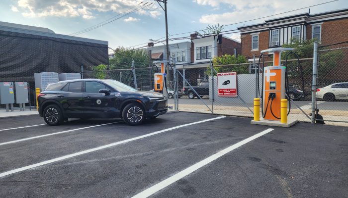 A black municipal electric car drives up to a new electric vehicle charging station at the Fleet Shop 258 facility.