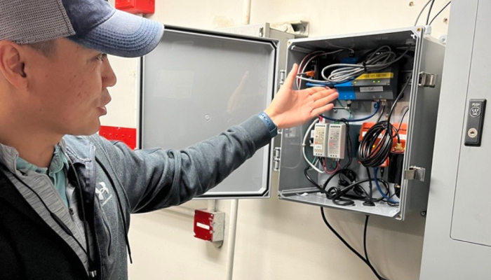 A man points to building automation controls installed on a wall