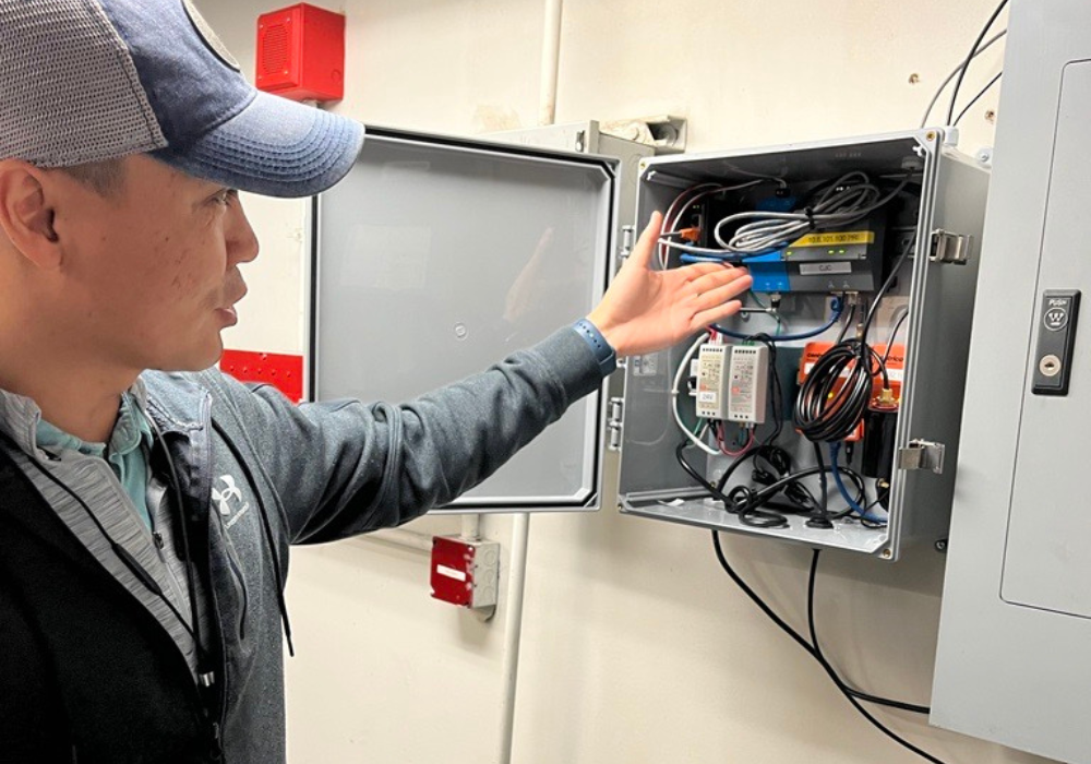 A man points to building automation controls installed on a wall