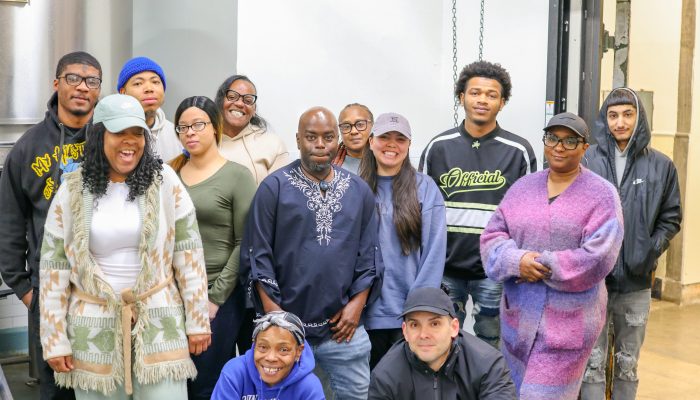 Apprentices in Triple Bottom Brewing's Future of Service Apprenticeship smiling together in front of equipment at Triple Bottom Brewery
